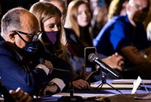 Image de Rudy Giuliani tenant son téléphone devant un haut-parler avec Trump au bout d fil.